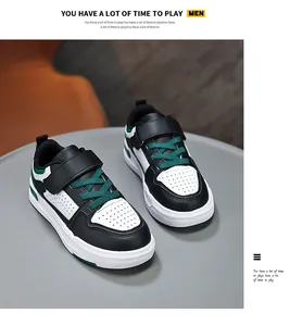 Close-up detail of children's black and white leather sneakers with green laces on a table.