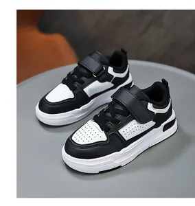 Detailed macro view of black and white children's leather sneakers on a gray table.