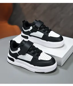 Close-up detail of black and white children's leather sneakers on white display box