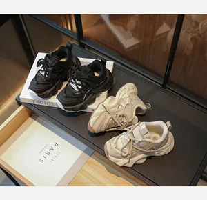 Close-up of black and beige kids' fashion sneakers with breathable mesh panels.