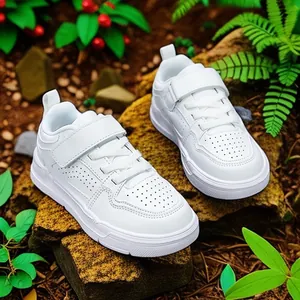 Classic white children's sneakers with Velcro and laces on a natural mossy rock background
