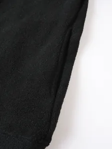Dettaglio macro del tessuto in pile nero e tasca laterale su felpa invernale da uomo