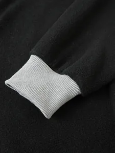 Dettaglio del polsino grigio a costine sulla manica della felpa in pile nero da uomo