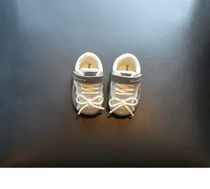 Detailansicht silberner Lauflernschuhe für Babys mit weißer Schleife.