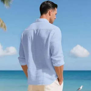 Vista trasera de una camisa de lino azul claro transpirable para hombre en la playa.