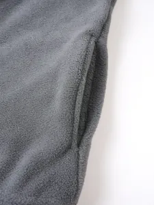 Primo piano del dettaglio della tasca laterale di un pullover in pile grigio scuro per uomo