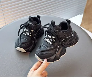 Close-up detail of black chunky children's sneakers with mesh texture and straps