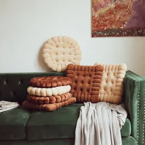 Cozy biscuit-shaped plush cushions in various colors arranged on a green velvet sofa