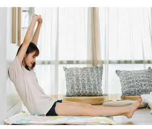 Young woman stretching on a floral vacuum compression storage bag in a bright home.