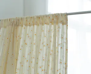 Close-up detail of small embroidered daisy patterns on a cream-colored cotton window curtain