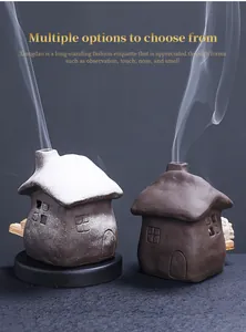 Detailed view of two ceramic house-shaped incense burners with natural rising smoke.