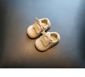 Beige babyschoentjes met zachte zool, gewatteerde neus en decoratieve strikjes