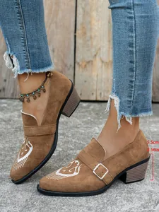 Gros plan sur des mocassins en daim marron à talon bloc avec broderie blanche et boucle
