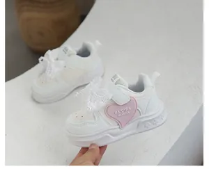 Detailed side view of white girls' sneakers with pink heart and lace pearl bow decoration
