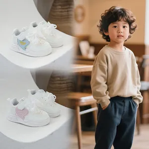 Detail of children's white sneakers with decorative lace bow and heart-shaped patch