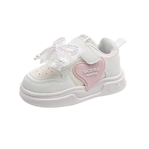 Detailed side view of white girls sneakers featuring a pearl lace bow and pink heart
