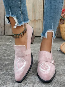 Détail de mocassins pointus en daim rose avec broderie blanche et boucle.