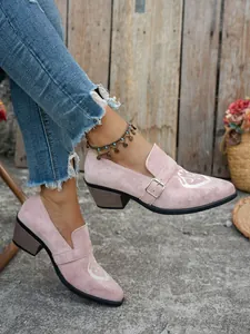 Gros plan sur des mocassins en daim rose avec broderie cheval blanc et boucle décorative.