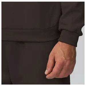 Zoom sur les détails des poignets et de l'ourlet côtelés d'un sweat marron homme