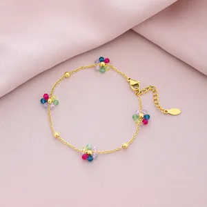 Close-up detail of a gold stainless steel bracelet with colorful crystal flower charms