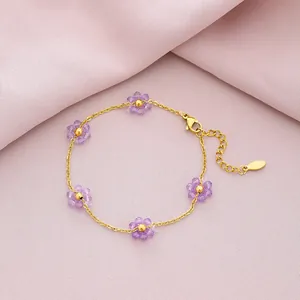Detailed view of gold titanium steel bracelet with purple crystal flower charms.