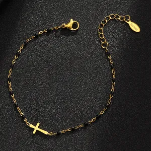 Nahaufnahme eines goldenen Armbands aus Edelstahl mit schwarzen Perlen und Kreuz-Anhänger