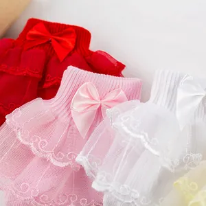 Gros plan sur les volants en dentelle double couche et les nœuds en satin des chaussettes.