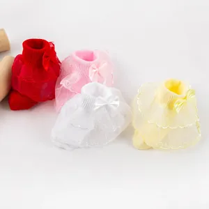 Détail de chaussettes pour bébé fille avec volants en dentelle et nœuds décoratifs.