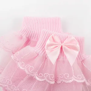 Gros plan sur des chaussettes roses pour bébé avec volants en dentelle et nœud en satin