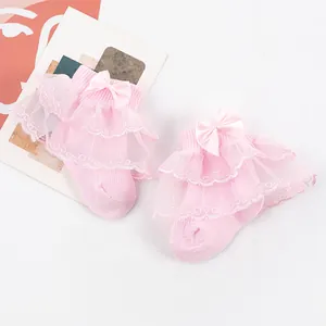 Détail de chaussettes roses pour bébé avec volants en dentelle double épaisseur et nœud