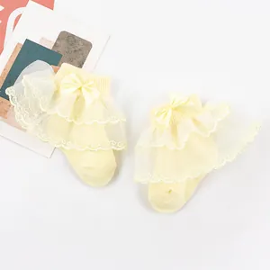 Détail de chaussettes bébé fille avec dentelle jaune à double couche et noeud en satin