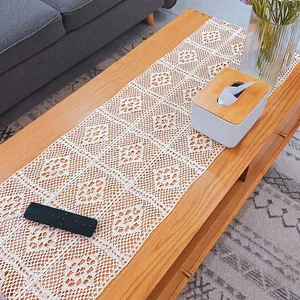 Detail of a beige vintage hollow lace crochet table runner on a natural wood surface