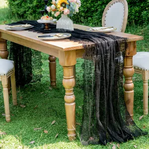Detailed view of elegant black lace table runner on wooden outdoor wedding table