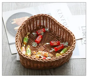 Heart-shaped imitation rattan basket filled with various colorful candies on a wooden table