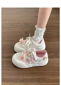Vista detallada de zapatillas blancas para niñas con lazo rosa estrella y suela gruesa