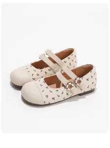 Detalle de zapatos Mary Jane crema con estampado floral, correas dobles y flores decorativas.