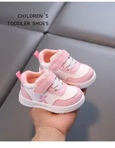 Detailed view of pink and white faux leather toddler sneakers held in hand for display