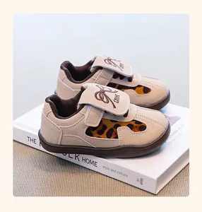 Detalle de zapatillas deportivas beige para niños con estampado de leopardo y un lazo