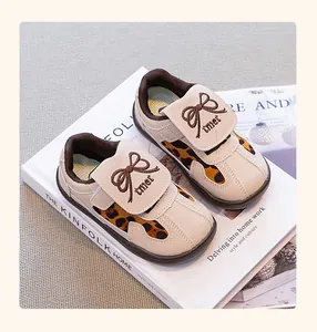 Vista detallada de zapatillas infantiles con estampado de leopardo y lazo sobre un libro