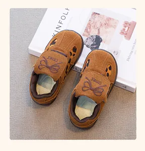 Primer plano de zapatillas infantiles de ante marrón con estampado de leopardo y lazo.