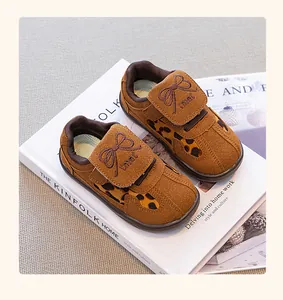 Primer plano de calzado deportivo marrón para niños con estampado de leopardo y lazo.