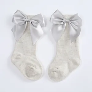High-quality detail of grey baby knee-high socks featuring oversized satin silver bows
