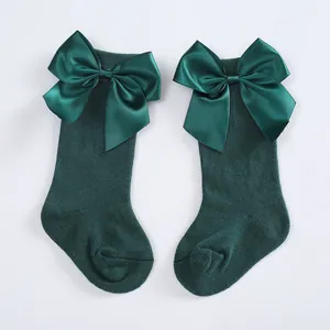 Detailed macro shot of dark green children's knee-high socks featuring large satin bows