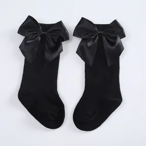 Close-up of black baby knee-high socks with large satin bows