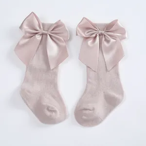 Close-up detail of baby girl knee-high socks featuring elegant large satin bow accents