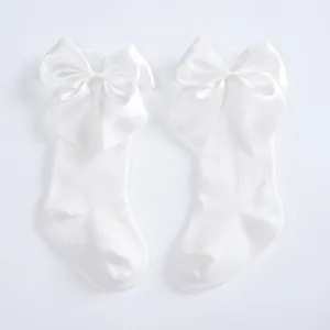 Detailed view of white children's knee-high socks with large elegant satin bows