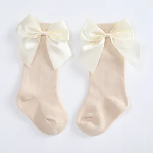 Pair of cream baby knee-high socks featuring oversized satin bow details