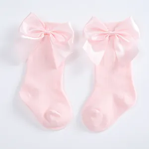 Soft pink baby knee-high socks featuring large elegant satin bow accents for infants