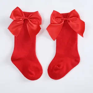 Detailed view of bright red children socks featuring large satin bows decoration
