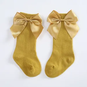 Detailed view of mustard yellow children's knee-high socks with large satin bows